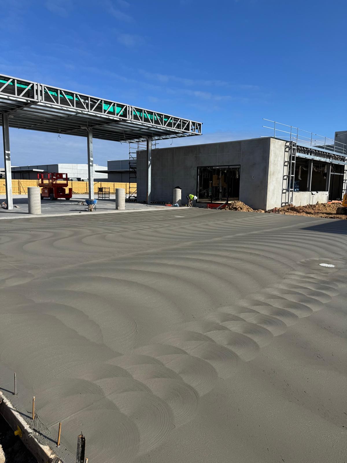 Fresh commercial concrete slab beside steel framing and concrete walls